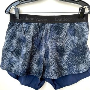 Outdoor Voices shorts, blue/black/gray patterned front, solid navy back, size L